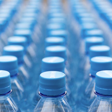 Photo by Jan van der Wolf Array of blue plastic water bottles with caps arranged in a pattern. Ideal for recycling and packaging themes.